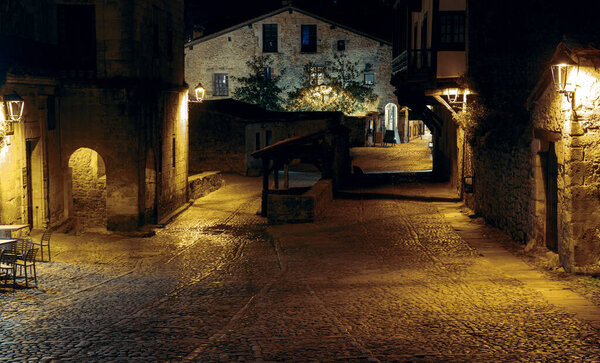 Night photo of a lonely alley from medieval times with cobblestone floors and stone walls in the beautiful Cantabrian town of Santillana del Mar.