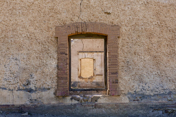 Wall in ruins with texture in which there is a window that reveals another wall with symmetrical window and next wall.
