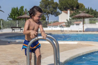Islak çocuk havuzdan yeni çıktı, suya baktı ve neşeyle gülümsedi.