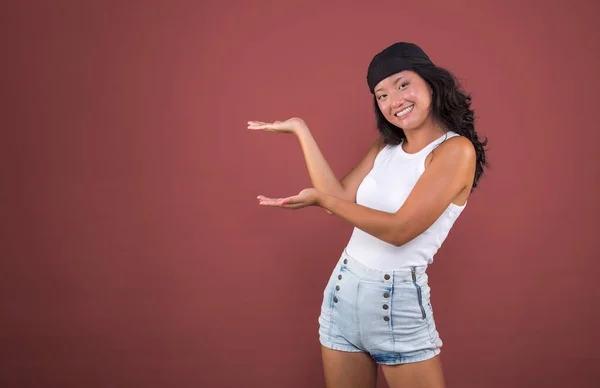 Bandanalı ve yalıtılmış tişörtlü genç Çinli kız bir şey gösteriyor..