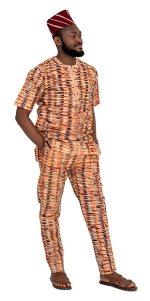 Geleneksel giyinmiş Afrikalı adam elini cebine atmış, beyaz arka planda tek başına duruyor.