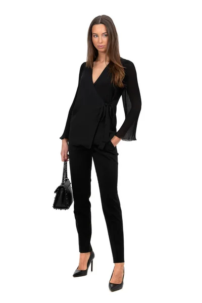 Siyah kostümlü bir kadın beyaz arka planda tek başına duruyor.