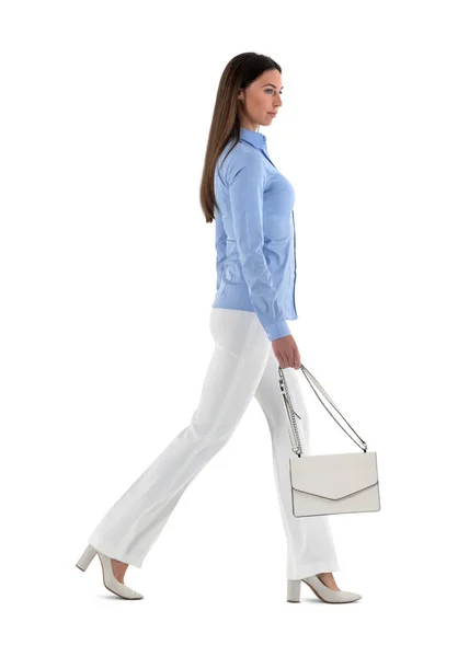 Genç zarif giyinmiş, şık giyimli, yüksek topuklu ayakkabılı, beyaz arka planda tek başına yürüyen bir kadın.