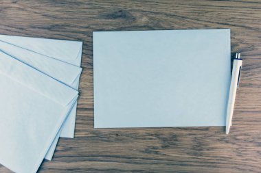 Giden yazışmalar: Ofisteki ahşap bir masanın üzerindeki boş beyaz zarflar, tonlama, bulanıklık