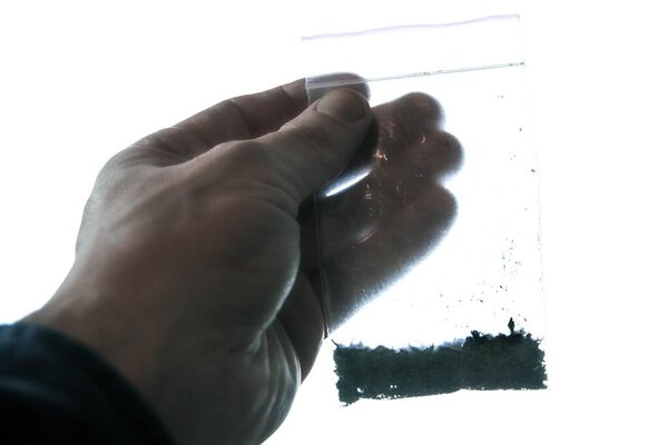 затемненная рука держит пакет с синтетической марихуаной