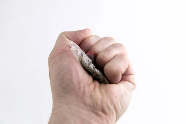 禁止半合法的吸烟混合物 一个装有合成大麻的袋子 被压在一个男人的拳头上 背景很浅 — 图库照片
