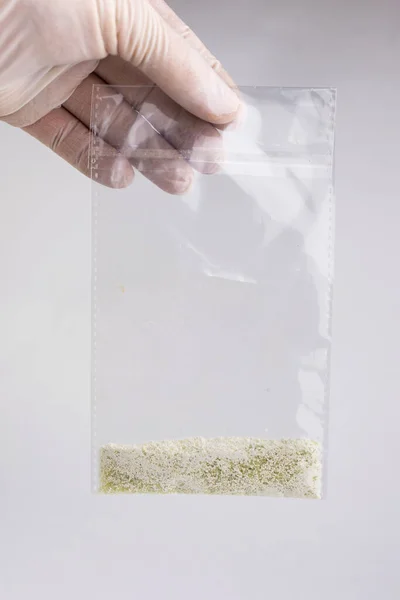 new drugs synthetic production: transparent bag with a narcotic crystalline substance, short focus, white background, changed contrast