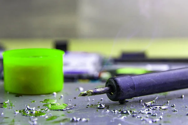 Isıtılmış demir üzerine reçine damlaları, teneke lehim, arka planda sökülmüş elektronik aygıtlar. seçici odak, kapat