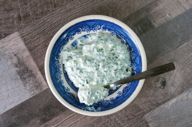 Akşam yemeği sosu: ahşap bir masada parlak bir porselen tabakta ekşi krema ve soğan.