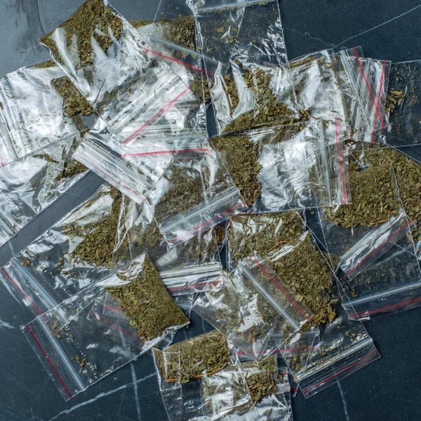 crime evidence: many packaged doses of cannabis lie on a dark surfac