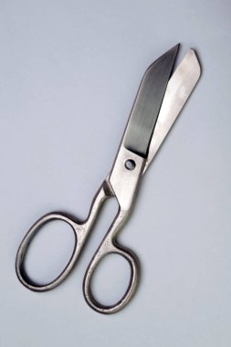 Beyaz suluboya kağıtlardan oluşan arka planda ağır antika parlak metal makas.