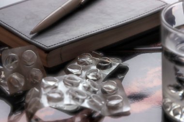 İntihar: not defteri, masada bir bardak su ve kabarcıklar, kısa odaklanma, tonlama