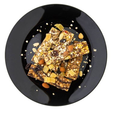 Vejetaryen diyeti: fındıklı, kuru üzümlü ve ballı mısır gevrekleri, siyah bir tabakta beyaz, kısa odaklı