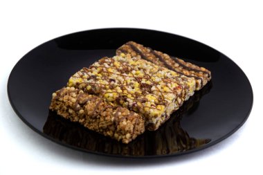 Vejetaryen diyeti: Beyaz ve kısa odaklı siyah bir tabakta kuru üzüm ve bal içeren birkaç mısır gevreği.