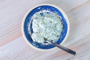 Akşam yemeği sosu: ahşap bir masada parlak bir porselen tabakta ekşi krema ve soğan.