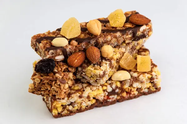 vegan dessert: several cereal bars with nuts, raisins and honey, on white, short focus