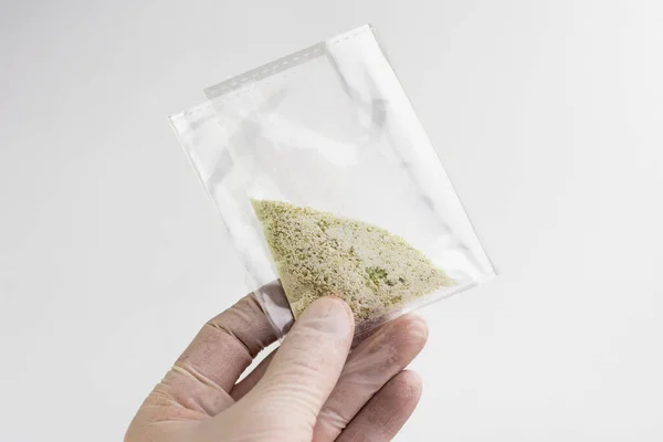 new drugs synthetic production: transparent bag with a narcotic crystalline substance, short focus, white background, changed contrast