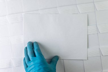 Ofisteki bir masanın üstünde duran boş beyaz zarflar dizisi, bir zarf adam ardardan çekip elinde tutuyor, kısa odaklı, tonlama