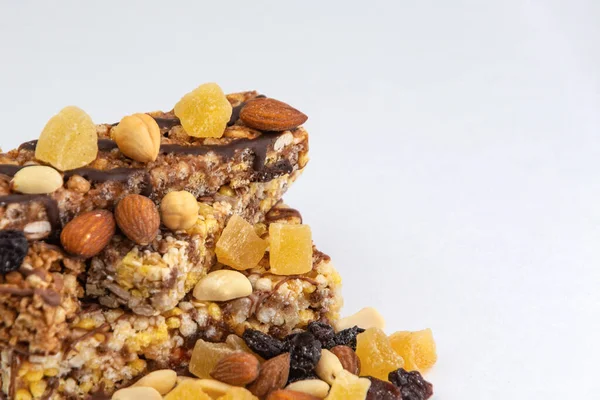vegan dessert: several cereal bars with nuts, raisins and honey, on white, short focus