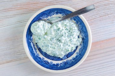 Akşam yemeği sosu: ahşap bir masada parlak bir porselen tabakta ekşi krema ve soğan.