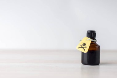 Zehirli çözeltisi olan siyah kavanoz, masada zehirli maddelerin içeriği hakkında uyarı işareti olan görgü kuralları.