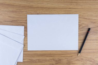 Giden yazışmalar: Ofisteki ahşap bir masada birkaç boş beyaz zarf, düşük kontrast