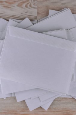 Giden yazışmalar: Ofisteki ahşap bir masada birkaç boş beyaz zarf, düşük kontrast