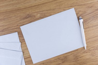 Giden yazışmalar: Ofisteki ahşap bir masada birkaç boş beyaz zarf, düşük kontrast