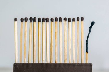 Bir sıra tahta kibrit, son kibrit yanmış ve bükülmüş.