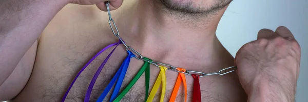 LGBT pride flag, built of colored ribbons tied on an iron chain around the neck of a man, short focus, on a white background