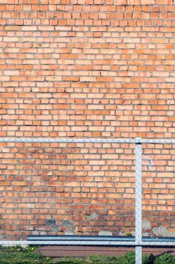 Metal bir çitin arkasındaki tuğla duvar.