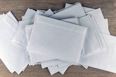 Giden yazışmalar: Ofisteki ahşap bir masanın üzerindeki boş beyaz zarflar, tonlama, bulanıklık