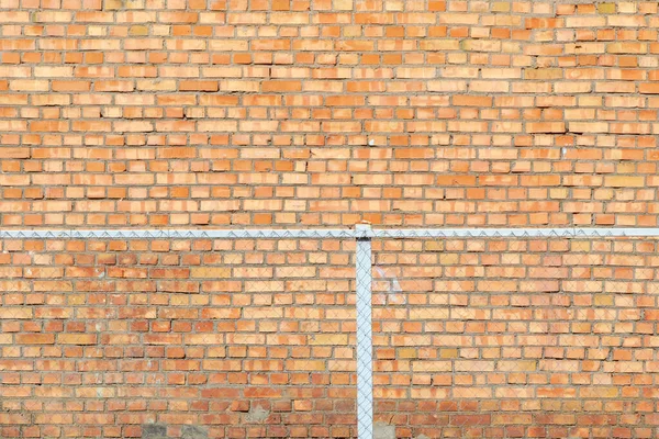 old brick wall behind a metal fence