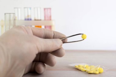 Sentetik psikotropik problemler: bir kişi masanın üzerinde diğer örneklerle birlikte yeni bir uyuşturucu örneği gösterir, kısa odaklı