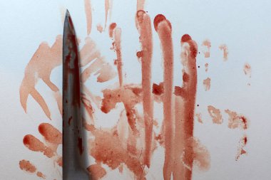 Arka planda kanlı bir bıçak var. Beyaz bir yüzeye kanlı el izleri bulaşmış.