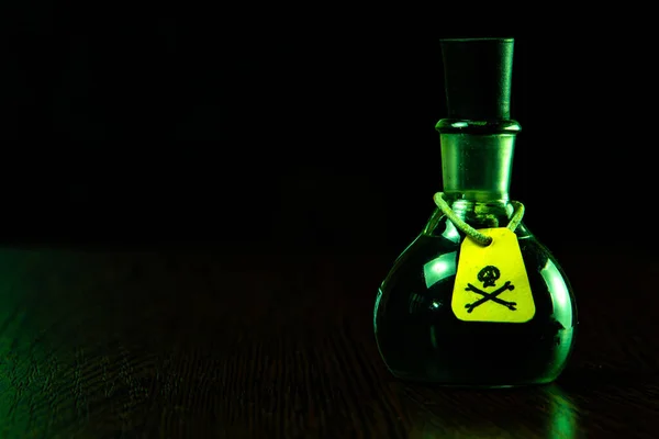 vial of poison with a hazard warning label, on a dark background, toning, short focus