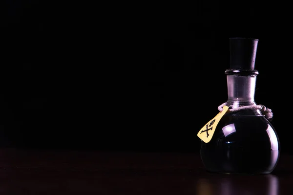 vial of poison with a hazard warning label, on a dark background, toning, short focus