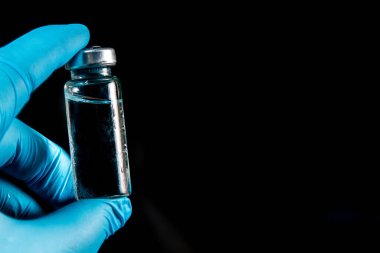 Sars-Kov-2 koronavirüs aşısı şeffaf cam ampul, don kaplı, koyu bir arka plan, kısa odak, ton