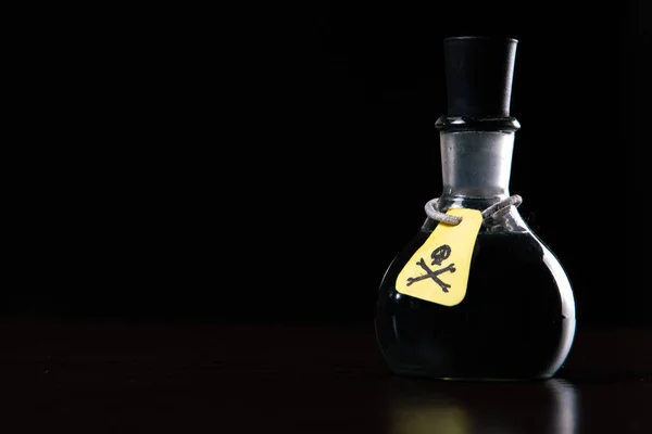 vial of poison with a hazard warning label, on a dark background, toning, short focus