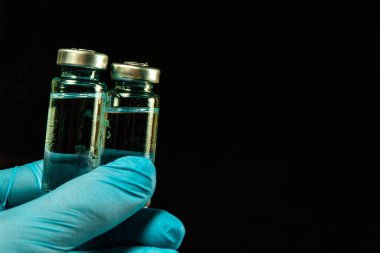 2 doz Sars-Kov-2 koronavirüs aşısı şeffaf cam ampuller, don kaplı, koyu bir arka planda, kısa odaklanma, ton 