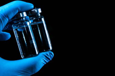 2 doz Sars-Kov-2 koronavirüs aşısı şeffaf cam ampuller, don kaplı, koyu bir arka planda, kısa odaklanma, ton 