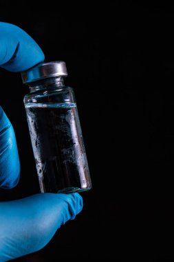 Sars-Kov-2 koronavirüs aşısı şeffaf cam ampul, don kaplı, koyu bir arka plan, kısa odak, ton