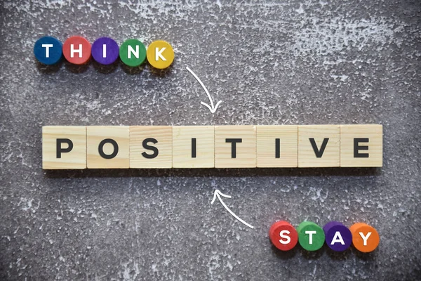 THINK POSITIVE and STAY POSITIVE text on the wooden blocks with white arrow lifestyle concept.