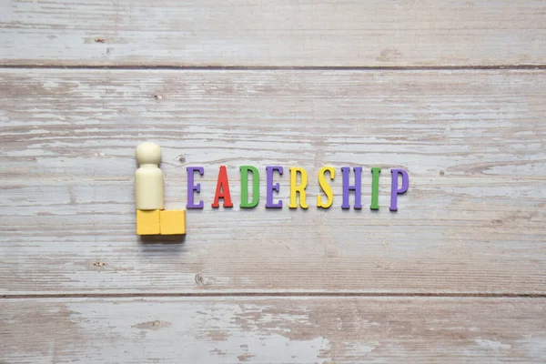Leadership 'in renkli alfabesi ve tek tahta bebek. İş konsepti.