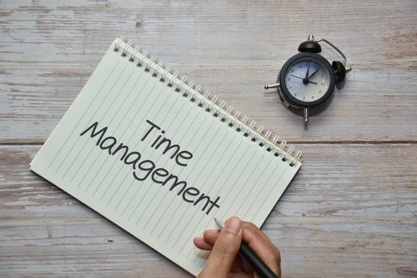 Not defteri ve analog alarm saatinde Time ManageMENT ile bir kalem tutuyorum. İş konsepti.