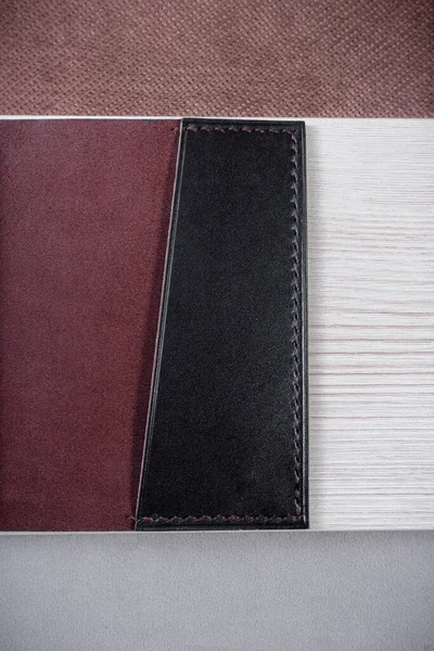 Leather passport cover lies on a geometric background consisting of brown and gray triangles with a light rectangle