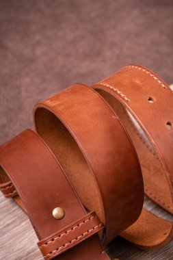 Geometrik arka planda tahtanın üzerinde altın tokalı turuncu deri kemer.