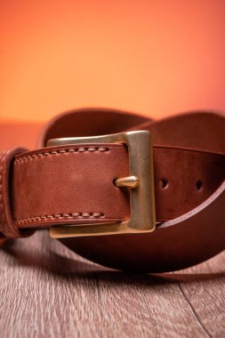 Deri kahverengi kemer, ahşap bir turuncu arka planda sonsuzluğun işareti olarak bükülmüş.