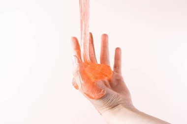 Baby hands play with toy anti-stress slime on beige background