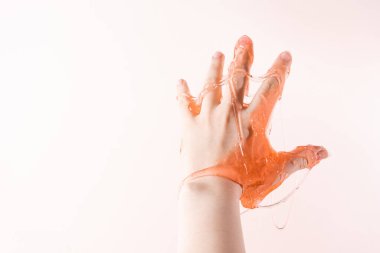 Çocuklar için bir oyuncak - açık pembe arka planda bir kızın parmaklarına yayılan balçık